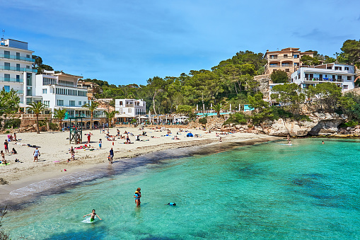 Santanyi, Spain - May 25, 2021: Bathers and empty hotels on the beach in the bay of Santanyi in Mallorca.