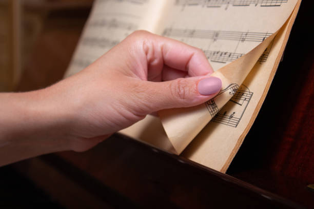 istock Pianist's hand turns sheet music page. Close-up. 1324047004