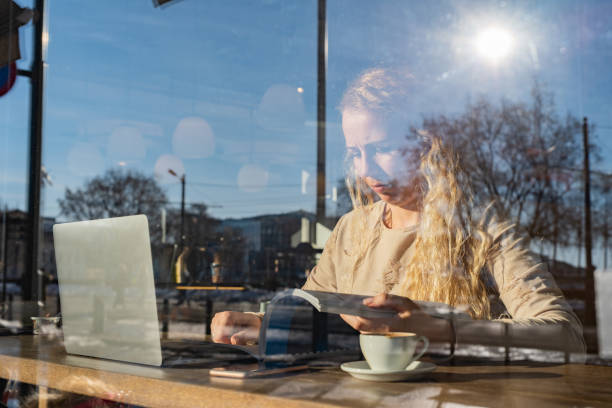 istock Young female student reading a book in coffee bar 1324053321