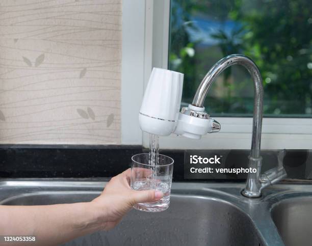 Woman Pouring Water Into Glass From The Water Filter In The Kitchen Stock Photo - Download Image Now