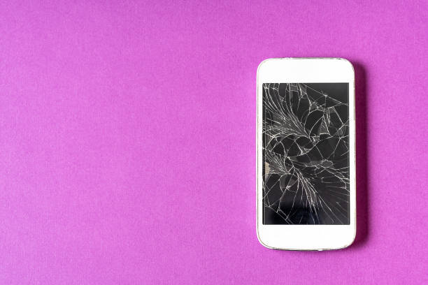 istock Broken mobile phone with cracked display on purple background. 1324055006