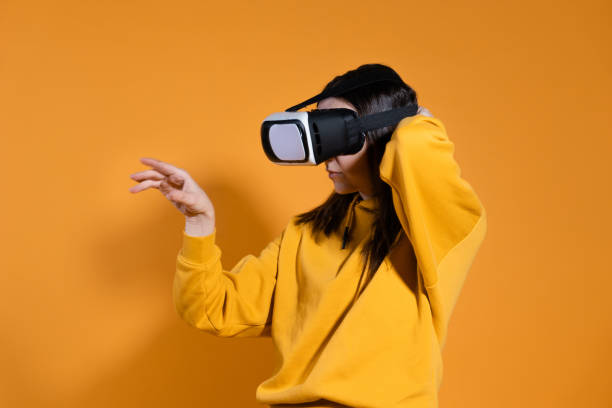 istock young woman with a virtual reality device on a yellow background. 1324056309