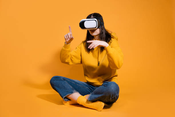 istock young woman with a virtual reality device on a yellow background. 1324056342