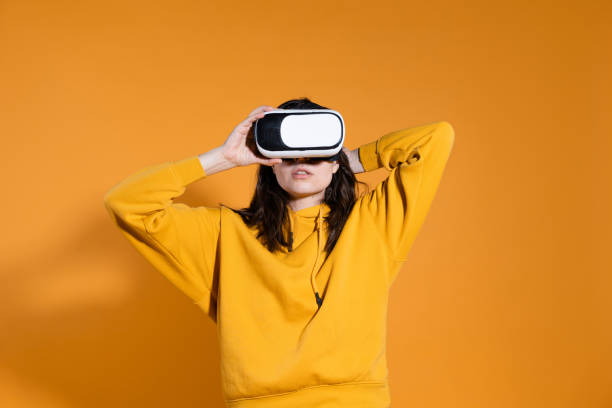 istock young woman with a virtual reality device on a yellow background. 1324056368