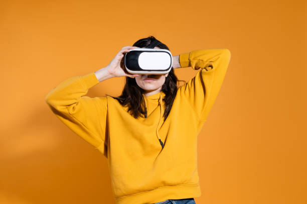 istock young woman with a virtual reality device on a yellow background. 1324056374