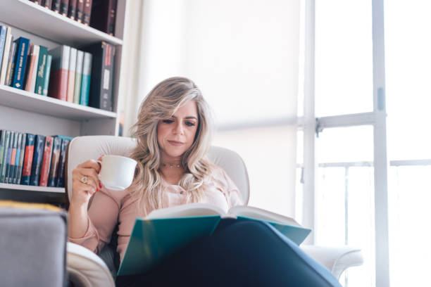 istock Woman reading a book at home 1324057091