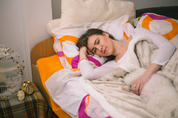 istock Young woman lying in bed in the evening and enjoying while having a cuddle with her adorable puppy she is holding. 1324057295
