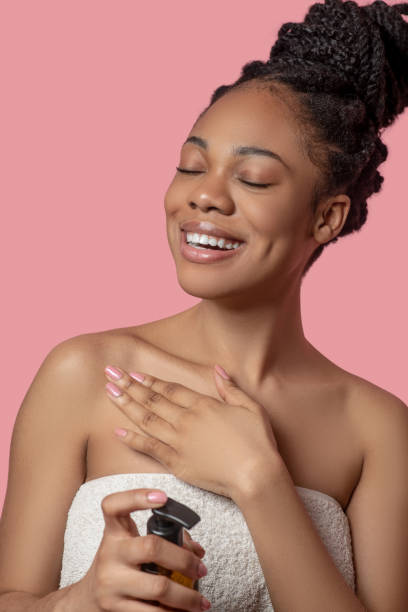 istock Dark-skinned woman applying moisturizing cream on her body before sunbathing and looking relaxed 1324058956