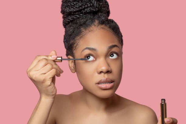 istock Dark-skinned woman doing make up and looking involved 1324058995