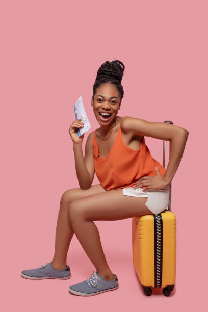 istock Dark-skinned woman holding a suitcase and a plane ticket 1324059094