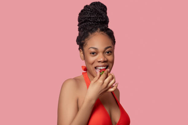 istock Dark-skinned woman eating strawberries and looking enjoyed 1324059239