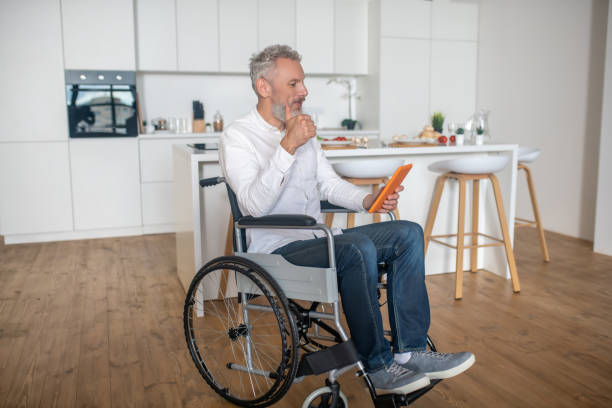 istock Gray-haired handicapped man with a tablet in hands 1324062437