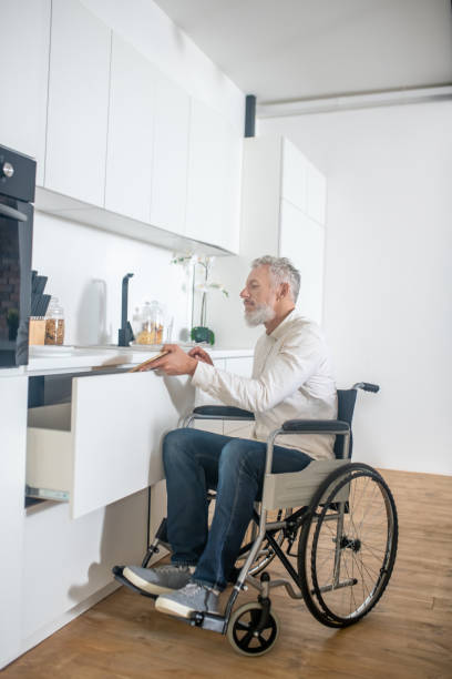 istock Gray-haired handicapped man in the kitchen getting the breakfast ready 1324062442