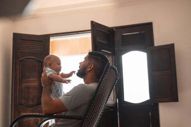 istock Father playing baby son rocking chair 1324063337