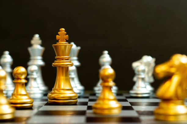 istock Gold king in chess game face with the another silver team on black background (Concept for company strategy, business victory or decision) 1324064411