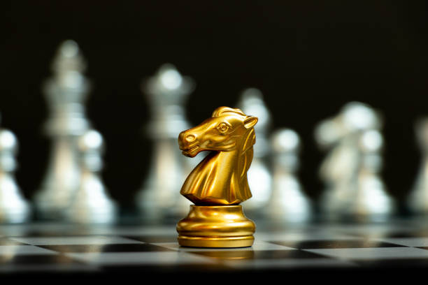istock Gold knight in chess game face with the another silver team on black background (Concept for company strategy, business victory or decision) 1324064421