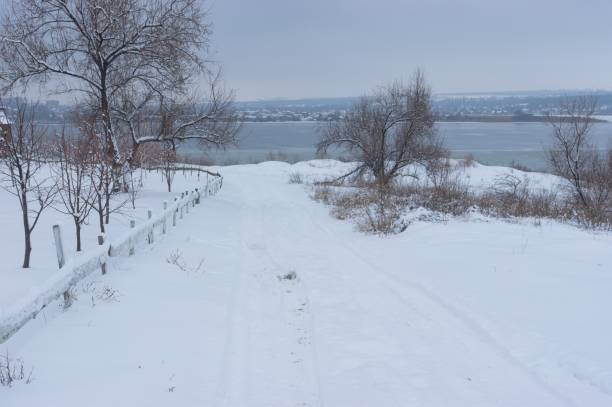 Carretera nevada que conduce al congelado río Dnipro cerca de la ciudad del mismo nombre en Ucrania - foto de stock