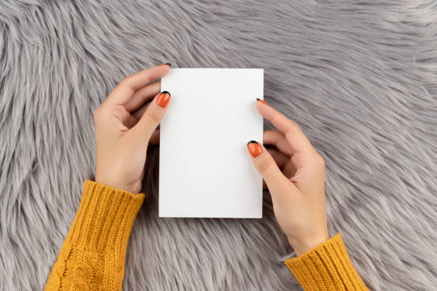 istock Manicured womans hand holding postcard on gray fluffy background 1324073910