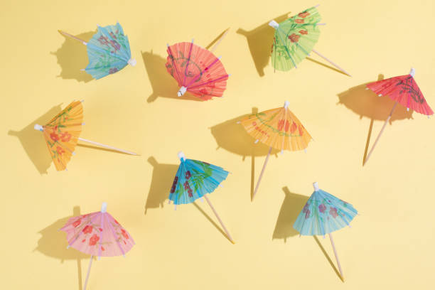 istock Multicolored cocktail umbrellas on yellow background in bright sunlight, summer party background. 1324074856
