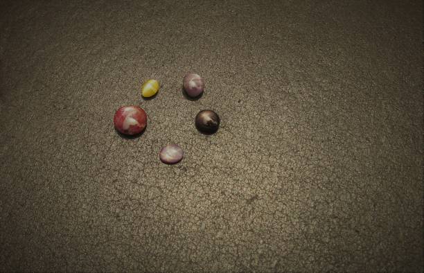 Metallic petanque balls and a small red jack on fine gravel
