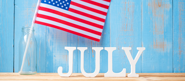 Texto de julio y bandera de los Estados Unidos de América sobre fondo de madera de la mesa. Día de fiesta de los E.E.U.U. de los conceptos de la independencia y de la celebración photo
