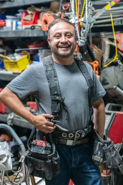 istock Smiling hispanic handyman posing at his shop with all his tools looking at the camera 1324077813