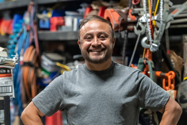 manitas hispano sonriente posando en su tienda con todas sus herramientas mirando a la cámara - trabajador emigrante fotografías e imágenes de stock