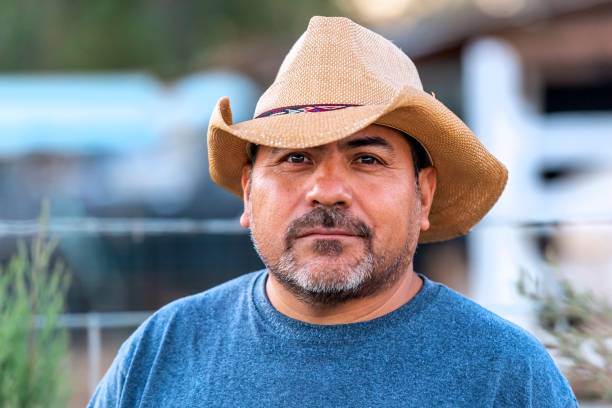 Hispanic farm worker posing wearing a cowboy hat looking at the camera
