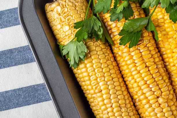 istock Step by step recipe. Home cooking baked corn in foil. Step 1 raw corn cobs on baking sheet. Homemade food concept. Vegetarian healthy eating. 1324081253