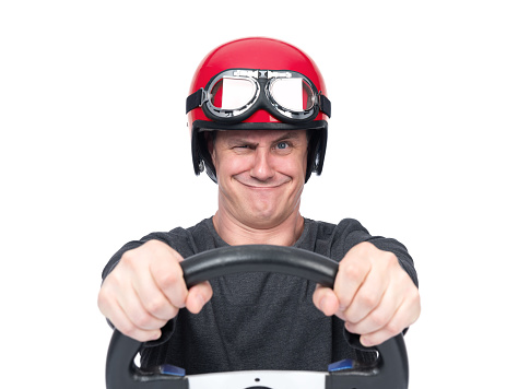 Emotional smiling man in red motorcycle helmet holding steering wheel, isolated on white background. File contains a path to isolation.