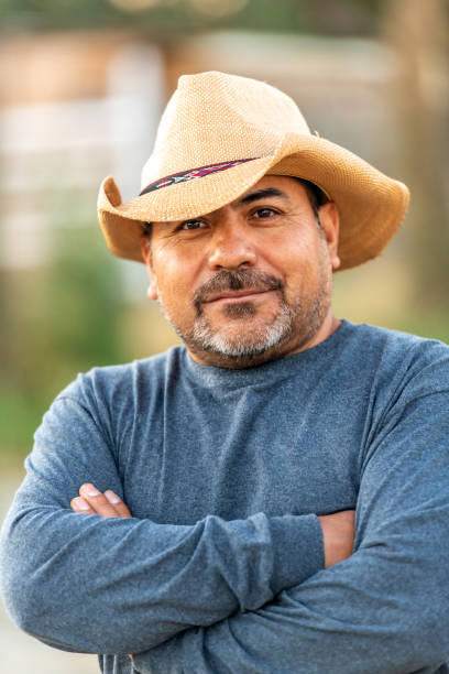 istock Hispanic farm worker posing wearing a cowboy hat looking at the camera 1324082468