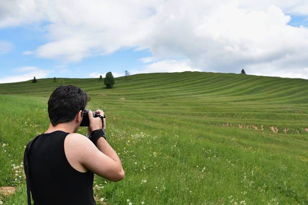 istock man photographs nature, meadow and sky 1324082628