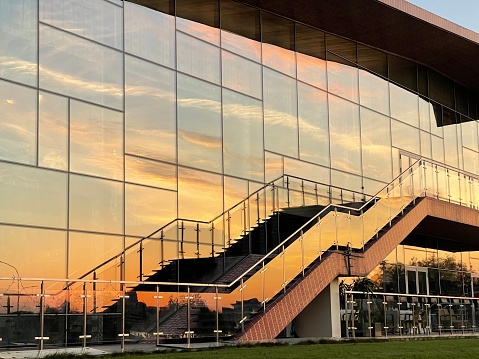 Reflection of the sunset sky in the glass wall of a building with a staircase