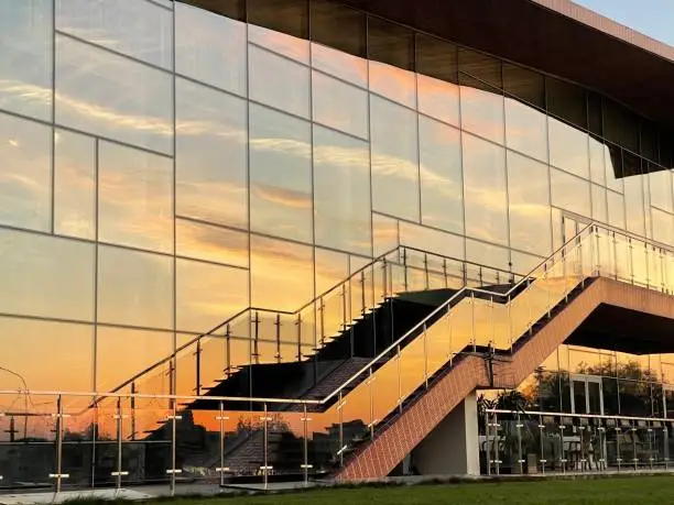 Photo of Reflection of the sunset sky in the glass wall of a building with a staircase