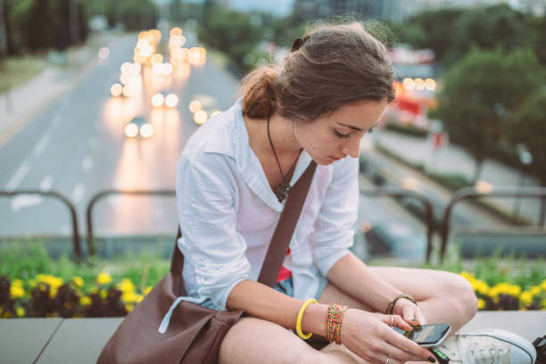 istock Young woman on the bridge texting on smartphone 1324086875