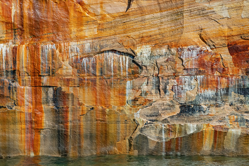Landscape of mineral stained cliff along the eroded sandstone shoreline of Lake Superior, Pictured Rocks National Lakeshore, Michigan’s Upper Peninsula, USA