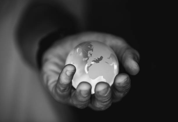Hand holding glass earth globe, black and white - Environment Concept
