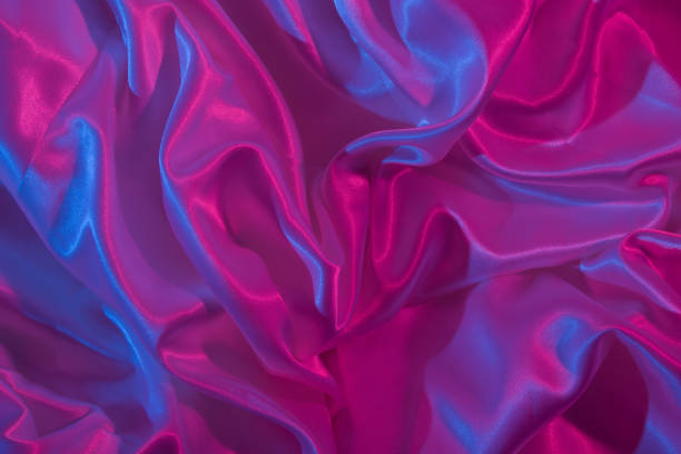 istock Top view of pleated santine fabric in neon light. Creative abstract background 1324088970