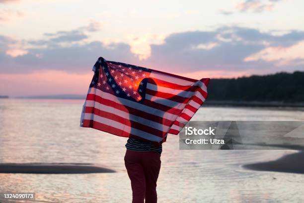A Woman With An American Flag On The Ocean At Sunset Independence Day The United States Celebrates July 4 Stock Photo - Download Image Now
