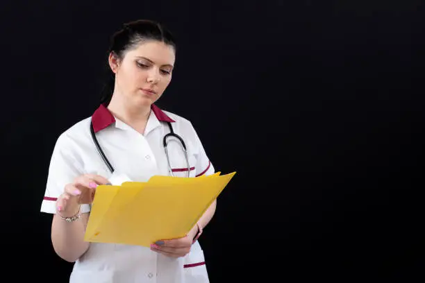 portrait of woman doctor with stethoscope and folder of documents on a dark background