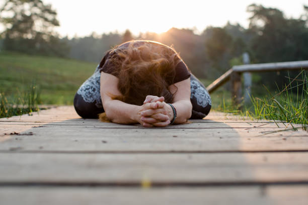istock Woman is standing on a boardwalk and doing yoga. 1324094420