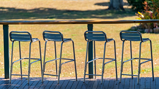 Chrome high stools at an outdoor bar looking towards gardens