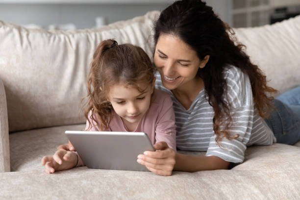 istock Smiling Hispanic mom and daughter use tablet at home 1324096506