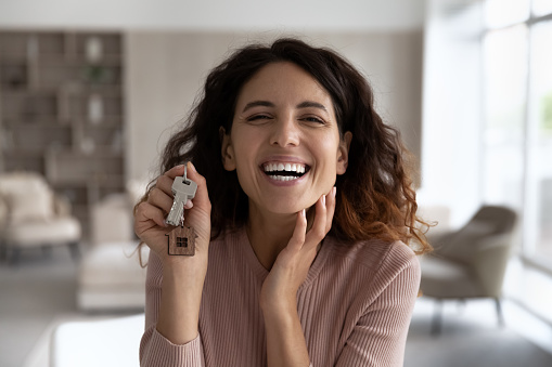 Headshot portrait of smiling Hispanic woman look at camera show keys to new home excited to move in. profile picture of happy Latino female renter buyer overjoyed to relocate. Renter, rent concept.