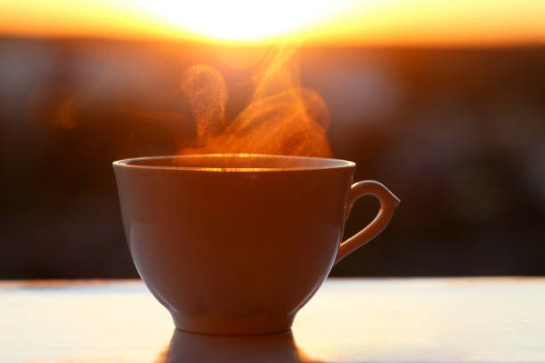 istock Hot coffee cup with smoke on sunrise background 1324096629