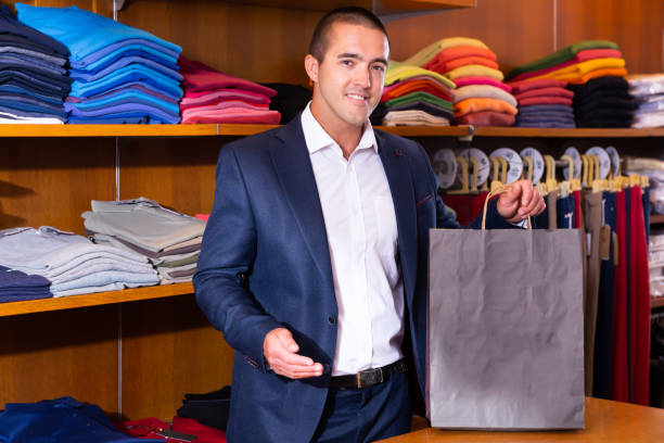 istock Smiling salesman holding out paper bag 1324097878