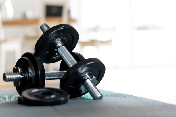 istock Dumbbells lie on a mat, bright background. Sport in the home office during remote work. 1324098522