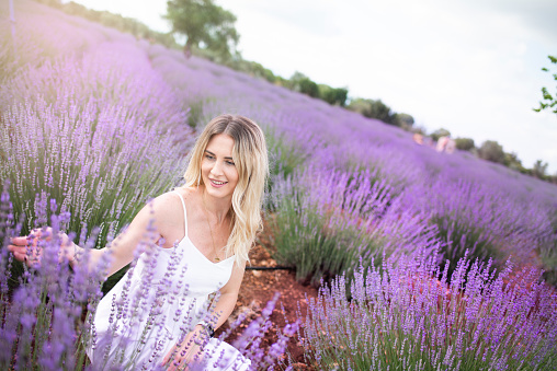 Young beautiful woman walking in a lavender field in a white dress.