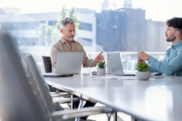 Two businessmen working with technology. Both are wearing casual clothing.