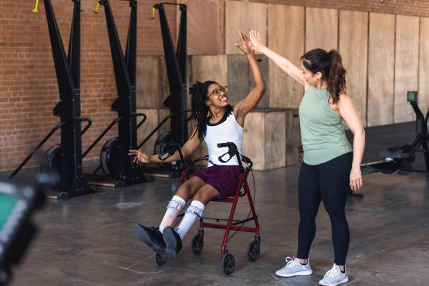 kuvapankkikuvat ja rojaltivapaat kuvat aiheesta nuori nainen pyörätuolissa high fives kuntosaliohjaaja - leg brace